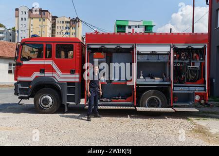 Ein dedizierter Feuerwehrmann bereitet einen modernen Feuerwehrwagen für den Einsatz in gefährdeten Bereichen vor, in denen ein Brand geschädigt wird, und demonstriert damit Bereitschaft und Engagement Stockfoto