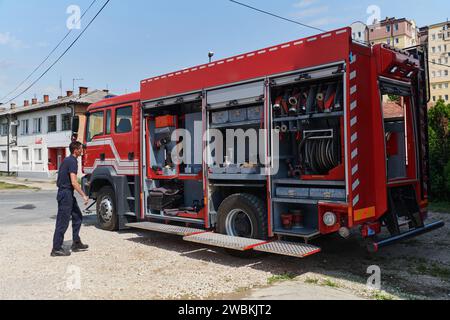 Ein dedizierter Feuerwehrmann bereitet einen modernen Feuerwehrwagen für den Einsatz in gefährdeten Bereichen vor, in denen ein Brand geschädigt wird, und demonstriert damit Bereitschaft und Engagement Stockfoto