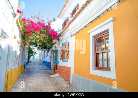 Ferragudo, Algarve, Portugal.26. september 2020. Traditionelle weiße Häuser mit Ziegeldächern in engen Gassen, die mit Bougainvillea-Blumen im geschmückt sind Stockfoto