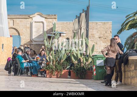 Touristen trinken Cocktails und spazieren über die alten Mauern mit der mittelalterlichen Festung des Heiligen Antonius, alten Gebäuden, Kakteen, Palmen in Bari Stockfoto