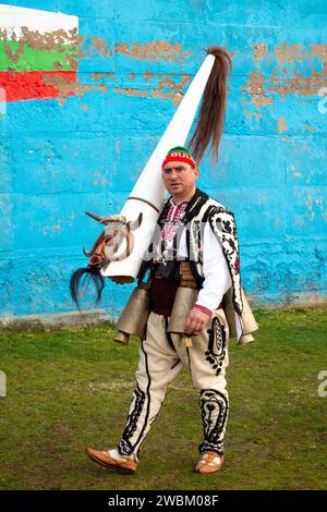 Einsame unmaskierte Kukeri-Tänzerin mit kompliziertem Kostüm und markanter, hoher konischer Maske auf dem Simitlia-Festival in Simitli, Bulgarien, Balkan, EU Stockfoto