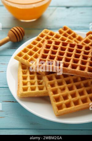 Belgische Waffeln auf blauem Hintergrund. Belgische Waffeln mit Honig und Milch. Vertikales Foto. Stockfoto