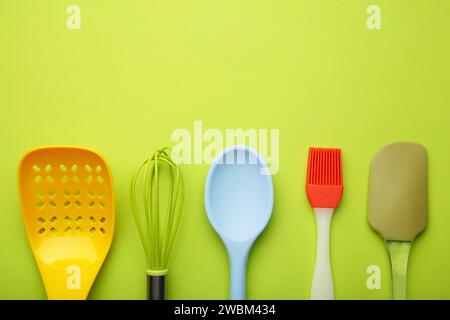 Verschiedene Küchenutensilien auf grünem Hintergrund mit Blick von oben. Kochgeräte. Stockfoto