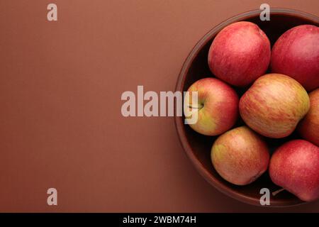 Viele rote Äpfel in einer runden Schüssel auf braunem Hintergrund. Draufsicht Stockfoto