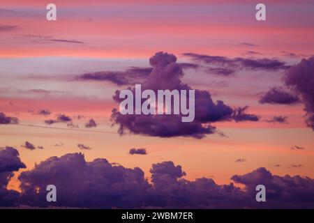 Ätherischer Himmel, der bei Sonnenuntergang in sanften Rosa- und Violetttönen gemalt ist, Wolken bilden eine dramatische Leinwand Stockfoto