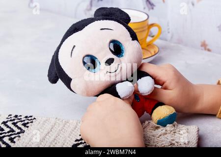 Das Kind hält ein altes mickey-Mausspielzeug mit nostalgischem Charme. Stockfoto