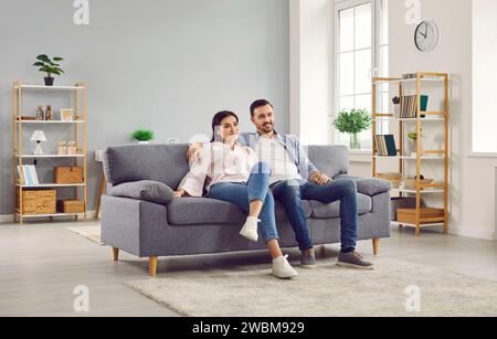 Paare, die zusammen Fernsehen, während sie auf der Couch im Wohnzimmer sitzen Stockfoto