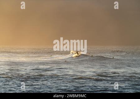 Surfer finden bei Sonnenuntergang am Ho'okipa Beach Harmonie mit dem Meer und fangen das Wesen von Mauis Surfparadies ein. Stockfoto