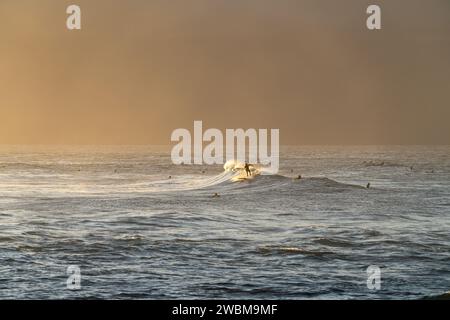 Surfer finden bei Sonnenuntergang am Ho'okipa Beach Harmonie mit dem Meer und fangen das Wesen von Mauis Surfparadies ein. Stockfoto