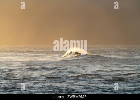 Surfer finden bei Sonnenuntergang am Ho'okipa Beach Harmonie mit dem Meer und fangen das Wesen von Mauis Surfparadies ein. Stockfoto