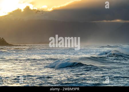 Die Wellen von Ho'okipa spiegeln das letzte Licht des Tages wider und schaffen eine traumhafte Landschaft für Surfer an Mauis Küste. Stockfoto