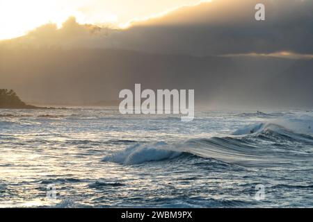 Die Wellen von Ho'okipa spiegeln das letzte Licht des Tages wider und schaffen eine traumhafte Landschaft für Surfer an Mauis Küste. Stockfoto