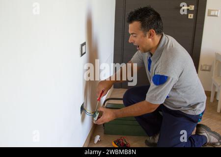 Bild eines Elektrikers, der einen elektrischen Stecker installiert und einen Stromschlag bekommt. Sicherheit am Arbeitsplatz Stockfoto