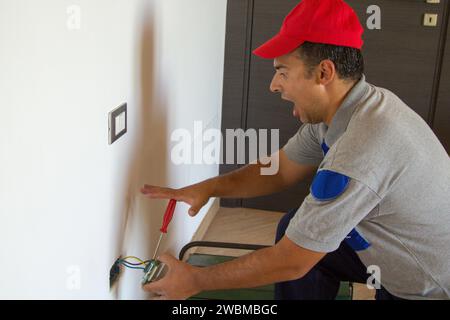 Bild eines Elektrikers, der einen elektrischen Stecker installiert und einen Stromschlag bekommt. Sicherheit am Arbeitsplatz Stockfoto