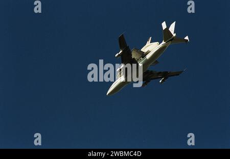 Das Shuttle Carrier Flugzeug mit dem Umlaufbahn Columbia oben wird von unten gesehen, während es durch den Himmel über der Space Coast von Florida schwingt, als es von der Cape Canaveral Air Force Station zum KSC zurückkehrt. Der Fährflug begann am 1. März in Kalifornien. Ungünstige Witterungsbedingungen hielten es am Boden in Dyess AFB, Texas, bis es nach Florida zurückkehren konnte. Sie landete vorübergehend auf dem CCAFS Skid Strip, bis Atlantis, das bereits auf der SLF gelandet war, übertragen werden konnte. Columbia kehrt von einem 17-monatigen Umbau- und Modernisierungsprozess als Teil eines Routinewartungsplans zurück. Stockfoto