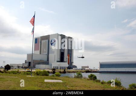 RAUMFAHRTZENTRUM KENNEDY, FLA. - Space Shuttle Discovery, auf einer Mobile Launcher Platform, nähert sich der Öffnung zum Hochregal 1 im Vehicle Assembly Building (VAB) im Kennedy Space Center der NASA. Ein Sicherheitshubschrauber schwebt in der Nähe. Der Blick ist von einem Bereich in der Nähe des NASA News Center, gegenüber dem Turn Basin. Rechts angedockt ist der Lastkahn, der externe Panzer von der Michoud Montageanlage in der Nähe von New Orleans nach Kennedy transportiert. Das Shuttle wird von Launch Pad 39B zurückgesetzt Im VAB wird der Discovery aus seinem externen Tank entlastet und in den Verteilergetriebe gehoben. Über oder über Ju Stockfoto