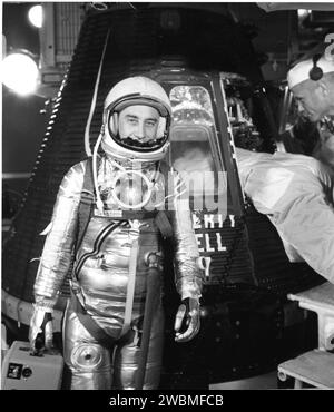 RAUMFAHRTZENTRUM KENNEDY, FLA. -- BEREIT FÜR DEN FLUG - auf Ebene 3 der Gantry auf Pad 5, Projekt Mercury Astronaut Virgil I. „Gus“ Grissom hält kurz inne, während ein Techniker die endgültige Anpassung in der Liberty Bell 7-Raumsonde durchführt, die Grissom am Freitag, den 21. Juli 1961, 118 Meilen in den Weltraum transportierte. Das große trapezförmige Beobachtungsfenster des Schiffes ist hinter dem Piloten zu sehen. Die Pilot Observer Camera, die den Kopf und die Schultern des Astronauten in Sicht brachte, sollte die Lichter auf der Flugereignissequenz durch den 5-Zoll-Parabolspiegel aus Plexiglas reflektieren, der an Grissoms Anzug befestigt war. Stockfoto