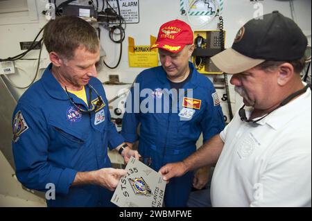 CAPE CANAVERAL, Fla. -- STS-135 Commander Chris Ferguson (links), Pilot Doug Hurley und Closeout Crew Lead Travis Tod Thompson von der United Space Alliance, sehen Sie sich die Tafel an, die vor der Luke des Space Shuttle Atlantis im Weißen Raum auf der Startfläche 39A des NASA Kennedy Space Centers platziert wird Ein Zugangsarm trägt den Weißen Raum, der sich am Shuttle befindet und den Zugang zum Mannschaftsraum ermöglicht. Die Astronauten sind in Kennedy, um an einer Probeprobe mit dem Titel Terminal Countdown Demonstration Test (TCDT) und entsprechender Schulung teilzunehmen. Atlantis A Stockfoto