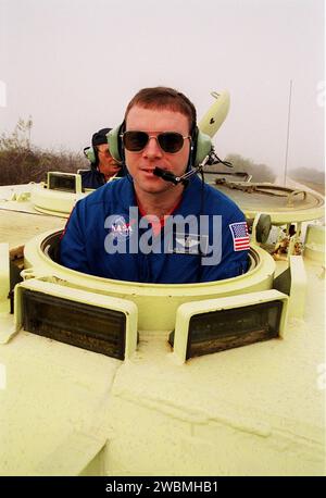 Der STS-102 Pilot James Kelly steigt in den Fahrersitz eines M-113 gepanzerten Trägers in der Nähe des Launch Pad 39B, der das Fahren üben wird. Im Hintergrund ist Captain George Hoggard, ein Ausbildungsoffizier bei der SGS Fire Services. Im Falle eines Notfalls vor dem Start auf der Anlegestelle könnte der Träger dazu genutzt werden, die Besatzung zu einem Bunker oder weiter zu transportieren. Die STS-102-Crew ist bei KSC, um an den Terminal Countdown Demonstrationstests teilzunehmen, zu denen auch ein simulierter Countdown gehört. STS-102 ist der achte Bauflug zur Internationalen Raumstation, der als Nutzlast die Multi- Stockfoto