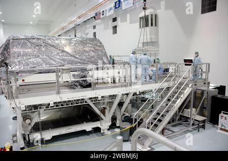 RAUMFAHRTZENTRUM KENNEDY, FLA. - Techniker in der Verarbeitungsanlage der Raumstation überprüfen die Platzierung des Kästchens Thermal Protection System Detailed Test Objective (DTO) auf dem leichten Mehrzweck-Experiment Support Structure Carrier (LMC). LMC und DTO fliegen mit dem Space Shuttle Discovery für die Mission STS-114. Das DTO enthält Fliesenproben, mit denen Astronauten neue Reparaturtechniken für das Wärmeschutzsystem auf der Umlaufbahn testen können. Das Startfenster für die Mission STS-114 ist vom 12. Mai bis 3. Juni. Stockfoto