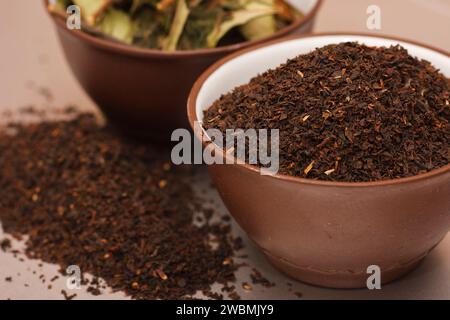 Ein großes, kalkhaltiges Blatt schwarzen Tees in zwei braunen Porzellantassen. Grüner Tee in Tonteetasse. Teeblätter zum Brühen. Stockfoto