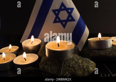 Steine, David-Stern, Kerzen, Stacheldraht, Israel-Flagge auf dunklem Hintergrund. Holocaust-Konzept. Stockfoto