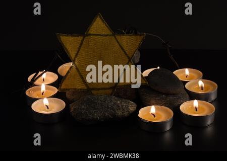 Steine, David-Stern, Kerzen, Stacheldraht, Israel-Flagge auf dunklem Hintergrund. Holocaust-Konzept. Stockfoto