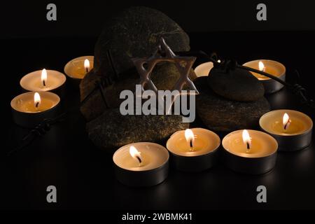 Steine, David-Stern, Kerzen, Stacheldraht, Israel-Flagge auf dunklem Hintergrund. Holocaust-Konzept. Stockfoto