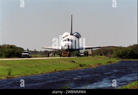 Begleitet von Arbeitern und Sicherheitskräften bewegt sich Atlantis auf dem Abschleppweg von der KSC-Shuttle-Landeanlage zur Orbiter-Verarbeitungsanlage. Atlantis kehrte nach der Landung auf der Edwards Air Force Base am 19. Februar auf einem Shuttle Carrier-Flugzeug aus Kalifornien zurück und beendete die Mission STS-98. Der Fährflug begann am 1. März; ungünstige Wetterbedingungen hielten ihn am Boden in Altus AFB, Okla., bis er nach Florida zurückkehren konnte. In der Orbiter Processing Facility wird Atlantis für die Mission STS-104 vorbereitet, den 10. Bauflug zur Internationalen Raumstation, der Ju starten soll Stockfoto