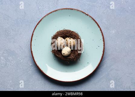 Nest mit frischen Wachteleiern auf blauem Hintergrund Stockfoto