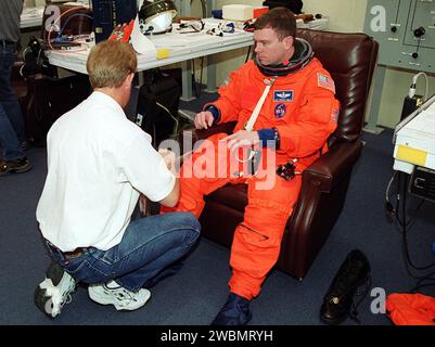 Der STS-102 Pilot James Kelly lässt seinen Startanzug während des Anzugs im Operations- und Checkout-Gebäude überprüfen. Die Crew ist bei KSC, um an den Terminal Countdown Demonstrationstests teilzunehmen, die einen Notausstieg vom Startplatz und einen simulierten Startzähler umfassen. STS-102 ist der achte Bauflug zur Internationalen Raumstation mit dem Mehrzweck-Logistikmodul Leonardo als Nutzlast. Außerdem wird die Expedition-Two-Crew an Bord sein und für eine viermonatige Amtszeit zur Raumstation fahren. Die Crew der Expedition One kehrt an Bord der Discovery zur Erde zurück. Starten Stockfoto