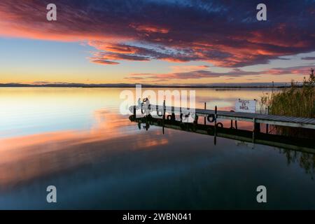 Junge Paare, die Fotos mit ihren Handys machen, die auf dem Pier des Albufera-Sees bei einem wunderbaren Sonnenuntergang sitzen, in Valencia, Spanien. Stockfoto