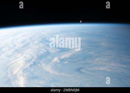 Iss070e035253 (4. Dezember 2023) --- der abnehmende Gibbous Mond ist auf diesem Foto von der Internationalen Raumstation, als er 262 Meilen über einem bewölkten Zentralasien umkreist, direkt über dem Horizont der Erde abgebildet. Stockfoto