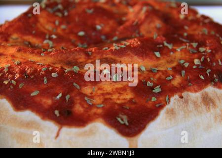 Eine Calzone mit Tomatensauce und Kräutern darauf. Stockfoto
