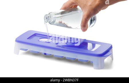 Sauberes Wasser gießt in eine Form für Eiswürfel, weißer Hintergrund. Eisbehälter mit versiegeltem Deckel aus Öko-Kunststoff, Großansicht. Stockfoto