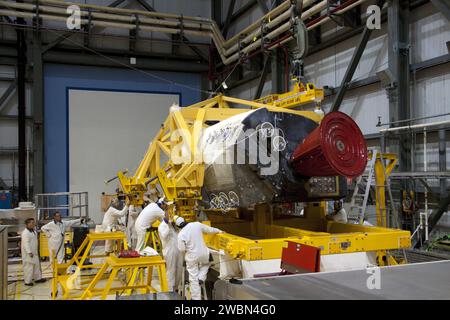 CAPE CANAVERAL, Fla. -- innerhalb der Orbiter Processing Facility-2 im Kennedy Space Center der NASA in Florida helfen Techniker, während ein großer Kran das linke Orbitalmanövriersystem (OMS) von Atlantis auf einen Träger senkt. Die Arbeit ist Teil der Übergangs- und Pensionierung des Shuttles Atlantis. Die OMS-Pods werden nach White Sands Space Harbor in New Mexico geschickt, wo sie einer vollständigen Deservicing- und Reinigungsaktion unterzogen und dann nach Kennedy zurückgegeben werden, um sie auf Atlantis wieder zu installieren. Atlantis wird für die Ausstellung im Kennedy Space Center Visito vorbereitet Stockfoto