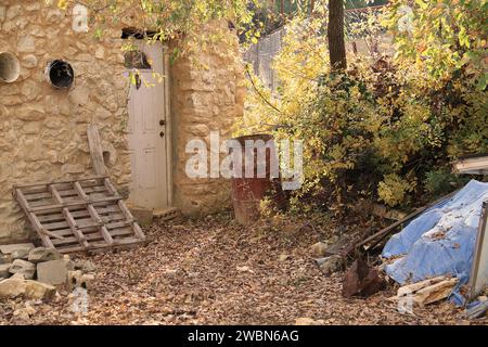 Ein rostiges rotes Fass in einem Hof mit Eicheln auf dem Boden. Stockfoto