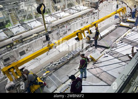 CAPE CANAVERAL, Fla. – In der Orbiter Processing Facility-2 im Kennedy Space Center der NASA in Florida befestigen Techniker einen großen Kran an den Roboterarm des Remote Manipulator Systems (RMS) im Nutzladeraum des Space Shuttle Atlantis, um ihn für den Ausbau vorzubereiten. Das RMS wird zum Johnson Space Center der NASA in Houston transportiert, wo es für zukünftige Raumflüge genutzt werden kann. Die Arbeit ist Teil der Übergangs- und Pensionierung des Shuttles Atlantis. Das Shuttle wird für die Ausstellung im Kennedy Space Center Visitor Complex vorbereitet. Stockfoto