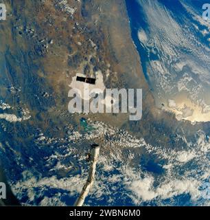 JOHNSON SPACE CENTER, HOUSTON, TEXAS -- STS-31 AN BORD SZENE -- das riesige Hubble Space Telescope (HST), das vor der bolivianischen, chilenischen und peruanischen Topographie etwa 332 nautische Meilen entfernt liegt, und das Space Shuttle Discovery, in dieser Szene durch seinen Arm des Remote Manipulator Systems (RMS) dargestellt, beginnen ihre relative Trennung im Raum. Das kreidefarbene Merkmal direkt unter HST heißt Salar de Uyuni. Der Titicacasee befindet sich oben rechts und der Fuope-See befindet sich unter teilweiser Wolkendecke in der Nähe des Endeffektors des RMS. Dieses Foto ist eines der ersten acht STS-31-Rahmen, die von N veröffentlicht werden Stockfoto