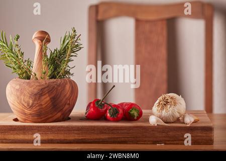 Gemischte Kräuter und Gewürze mit einem Stößel und Mörtel auf einem hölzernen Schneidebrett in einer Küche. Stockfoto