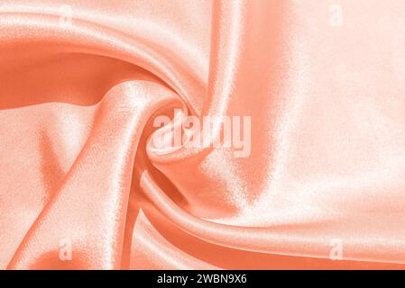 Farbe des Jahres 2024. Pfirsichfarbener Hintergrund in Pastellfarben. Trendige abstrakte Seidentapete. Moderner Seidenstoff im Hintergrund. Stockfoto