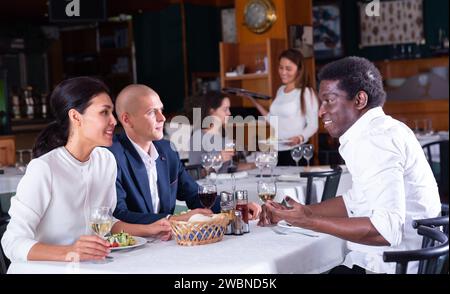 Positive Gäste, die im Café essen und trinken Stockfoto