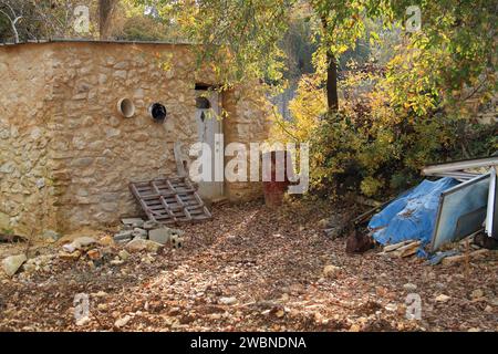 Ein rostiges rotes Fass in einem Hof mit Eicheln auf dem Boden. Stockfoto