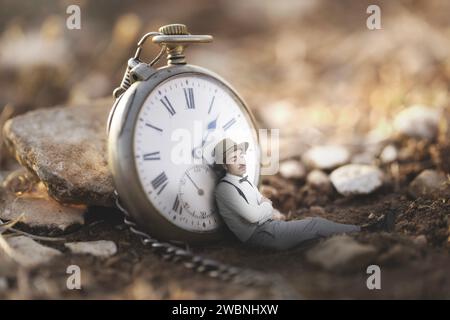 Der Mensch schläft ein und lehnt sich an eine große Uhr, abstraktes Konzept Stockfoto