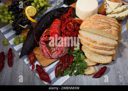 Geräucherter Stör, Hummer, Krebse, Brot, Käse und Früchte auf Holzoberfläche Stockfoto