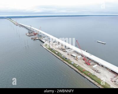 In dieser Luftaufnahme arbeiten Crews mit Orion Marine Construction an der Fertigstellung der Indian River Bridge in westlicher Richtung, während der tägliche Verkehr entlang der ausgebauten ostwärts gerichteten Fahrspuren der Brücke zum Kennedy Space Center der NASA in Florida am Montag, den 27. November 2023, bewegt. Die Brücke überquert die Indian River Lagoon und verbindet Kennedy und die Cape Canaveral Space Force Station über die State Road 405/NASA Causeway in Titusville mit dem Festland. Die neue Hochhausbrücke dient als Haupteingang und Ausgang zum Weltraumzentrum für Mitarbeiter und Besucher. Die neuen Brückenspannungen ersetzen ein Paar o Stockfoto