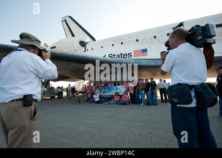 Die NASA und das Personal der Auftragnehmer werden unter dem Flügel des Space Shuttle Atlantis in der Kennedy Space Center Shuttle Landing Facility (SLF) fotografiert, kurz nachdem Atlantis (STS-135) am frühen Donnerstagmorgen, 21. Juli 2011, in Cape Canaveral, Fla. Insgesamt verbrachte Atlantis 307 Tage im Weltraum und legte während seiner 33 Flüge fast 126 Millionen Meilen zurück. Atlantis, der vierte Orbiter, startete auf seiner ersten Mission am 3. Oktober 1985. Stockfoto