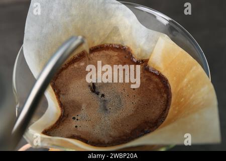 Gießen Sie heißes Wasser in eine chemex-Glaskaffeemaschine mit Papierfilter und Kaffee, Nahaufnahme Stockfoto