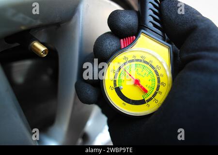 Der Fahrzeugmechaniker oder Fahrer überprüft den Reifendruck mit einem Reifendruckmesser. Fahrzeugwartungskonzept Stockfoto