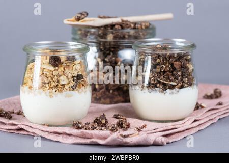 Dresden, Deutschland. Januar 2024. Gläser mit einer pflanzlichen Joghurt-Alternative und Müsli stehen auf einem Tisch. Sie sind verzehrfertig, attraktiv verpackt und enthalten oft viel Zucker, Salz, Fett und Zusatzstoffe, aber wenig wichtige Nährstoffe. Stark verarbeitete Lebensmittel landen sehr oft im Warenkorb. Experten sehen Risiken, die mit hohem Konsum verbunden sind (zu dpa 'oft serviert, selten gesund: Hochprozessierte Lebensmittel') Credit: Sebastian Kahnert/dpa/Alamy Live News Stockfoto
